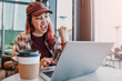 © EdNurg - Energetic young woman screaming and clenching fist, celebrating success while looking at a laptop screen in a cafe