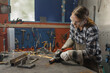 © 24K-Production - Woman mechanic working in a small home business metalworking workshop, grinding steel with circular saw. Economy and employment concepts.
