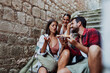 © Novak - Three young tourists enjoying pizza while sitting on stone stairs in the old town