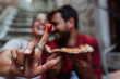 © Novak - Close up of a young couple eating pizza outside, dipping finger in tomato sauce.