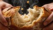 © phj.domingos - Freshly baked bread being torn open by hands. A close-up shot shows the texture of the bread and the hands that are pulling it apart.