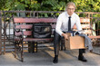 © Pixel-Shot - Fired male office worker with personal stuff sitting on bench outdoors