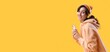 © Pixel-Shot - Happy young woman with face piercing and mobile phone listening to music on yellow background with space for text