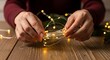 © Ilham - Hands decorating a wooden table with glowing fairy lights