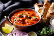 © annapustynnikova - Spicy chicken curry with naan bread, fresh herbs, lime wedges and aromatic spices. Dark background. Close up.