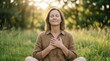 © AspctStyle - Mature woman meditating with closed eyes and hands over heart, sitting peacefully in sunlit natural meadow, mental wellness and self-connection concept.