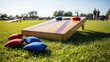 © Nataly - A wooden cornhole board with red and blue bean bags on a green lawn. Outdoor summer lawn game activity on a sunny day. Recreation and leisure concept