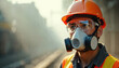 © miss irine - Industrial worker wears protective mask, goggles, hard hat and vest. Man breathes filtered air in hazardous air quality area. Protective gear prevents dust inhalation during work.