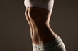 © vladimirfloyd - Side view of a woman’s torso with toned abdomen and slim waist, studio shot on a dark gray background
