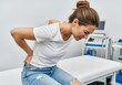 © nasima - Young woman suffering from severe back pain in a medical clinic.