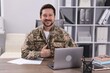 © New Africa - Military education. Student in soldier uniform showing thumbs up at wooden desk indoors