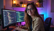 © Pete - Young woman programmer smiling working on code at desk. Wears glasses, sits in front of multiple computer monitors with colorful text. Room neon purple, blue lighting, creating modern ambiance.