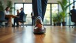 © Maryna - Businessman walks on wooden office floor, wearing striped socks and brown shoes. Colleagues and plants blur in background, modern workspace.