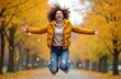 © Maryna - Young woman jumps joyfully in air amidst falling autumn leaves. Wears jeans, yellow puffer jacket. Curly hair woman enjoys outdoor fall season fun. Laughs with arms spread wide, feeling happy, free.
