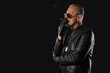 © Pixel-Shot - Stylish old man in leather jacket smoking cigar on black background