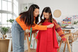 © Pixel-Shot - Happy Asian mother taking daughter's measurements in sewing studio