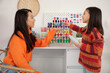 © Pixel-Shot - Happy Asian mother and her daughter choosing colourful thread spools in sewing studio