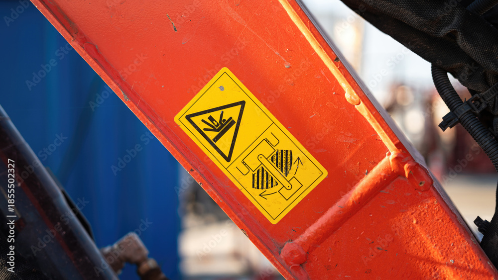 Safety caution sign on the backhoe front part, instruciton for keep out from the swing radius to prevent the accident. Safety sign on the industrial machine, close-up.