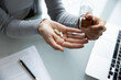 © fizkes - Workday wellness moment. Close up young female employee sit at office desk pull pills capsules from medical jar into hand. Daily routine taking vitamins supplements medication for health care concept