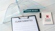 © bung - Transparent umbrella and documents on wooden table for insurance claim review and processing with pen and clipboard