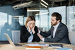 © Liubomir - Businessman comforts upset female colleague at her office desk, offering empathy and emotional support as she copes with burnout, stress and workplace fatigue