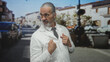 © Krakenimages.com - Man scientist with gray long hair and beard wearing lab coat and glasses points finger to chest on street; confidence authority experience.