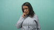 © Krakenimages.com - Middle age brunette woman touches chin with finger and appears to consider in teal studio portrait, striped shirt visible; thoughtful reflection.