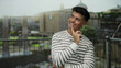 © Krakenimages.com - Young man smiling in front of ancient roman ruins, dressed in a striped shirt, with blurred cityscape and historic architecture in the background.