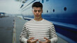 © Krakenimages.com - Man standing focused on breathing exercise by cruise liner at port, wearing striped shirt, closed eyes suggest relaxation, vivid depiction of mindfulness outdoors.