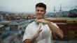 © Krakenimages.com - Hispanic man gestures timeout with headphones in a seaside port, convey a relaxed vibe against the backdrop of colorful shipping containers and industrial cranes.