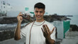 © Krakenimages.com - Young man holding camera on seaside promenade showcasing photography in a casual outdoor setting under clear skies.