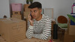 © Krakenimages.com - Young man in striped shirt having phone call surrounded by moving boxes inside new apartment.