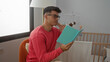 © Krakenimages.com - Young man reading in a cozy bedroom nursery with baby crib and soft lighting, embodying a serene and thoughtful moment indoors.