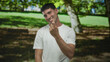 © Krakenimages.com - Young smiling hispanic man beckoning with finger in lush forest park clearing under bright sunlight; invitation.