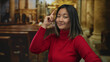 © Krakenimages.com - Smiling young chinese woman in red sweater gesturing in an ornate indoor church setting, suggesting a thoughtful or insightful idea.