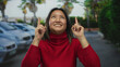 © Krakenimages.com - Woman in red sweater smiling and pointing upwards on a city street with cars in the background, conveying positivity and hope in an urban outdoor setting.