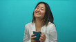 © Krakenimages.com - Woman smiling holding blue cup on isolated blue background wearing white blazer indicating a cheerful and relaxed mood.