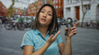 © Krakenimages.com - Woman in blue shirt grips hand exerciser on a busy city street with bicycles parked nearby among urban architecture.