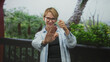 © Krakenimages.com - Woman caucasian blond wearing glasses and denim shirt raising hands with thumbs up and smiling on building balcony; warm friendly joy.
