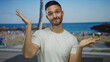 © Krakenimages.com - Young hispanic man in white shirt making a shrugging gesture on a sunny beach with blue sky and ocean in the background showing a casual and relaxed vibe outdoors.