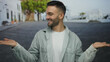 © Krakenimages.com - Young man in casual clothing smiles with hands extended on a charming urban street, showcasing a relaxed decision-making gesture in a hispanic city setting outdoors.