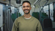 © Krakenimages.com - Young hispanic man smiling confidently on a bus while gesturing at his head in a casual sweater showcasing a lively and indoor commuting scene with a cheerful vibe and ambient lighting