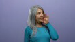 © Krakenimages.com - Senior woman with grey hair speaks animatedly against an isolated purple background wall, conveying emotion and expression.