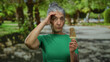 © Krakenimages.com - Senior woman with grey hair enjoys ice cream in a sunny park, wearing a green shirt, capturing a peaceful outdoor moment in nature.