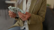 © Krakenimages.com - Woman counting american dollars in an office setting, featuring hands holding banknotes indoors, depicting finance and business themes in a professional workplace.