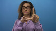 © Krakenimages.com - Hispanic transgender woman wearing purple blouse forms l shape gesture with raised hand in blue studio; mockery.