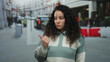 © Krakenimages.com - Woman signaling with her thumb on a busy street captures a moment of ponder, showcasing her expression amidst an urban outdoor backdrop.