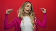 © Krakenimages.com - Woman displays hands in a gossip gesture inside a studio with young blonde energy against a red background on an isolated wall.