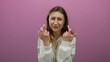 © Krakenimages.com - Young woman crossing fingers against isolated pink background, expressing hope and wishful emotion.
