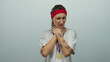 © Krakenimages.com - Woman in a white shirt with red headband and medal looks uncomfortable holding her throat against a white background, conveying a sense of discomfort or strain.